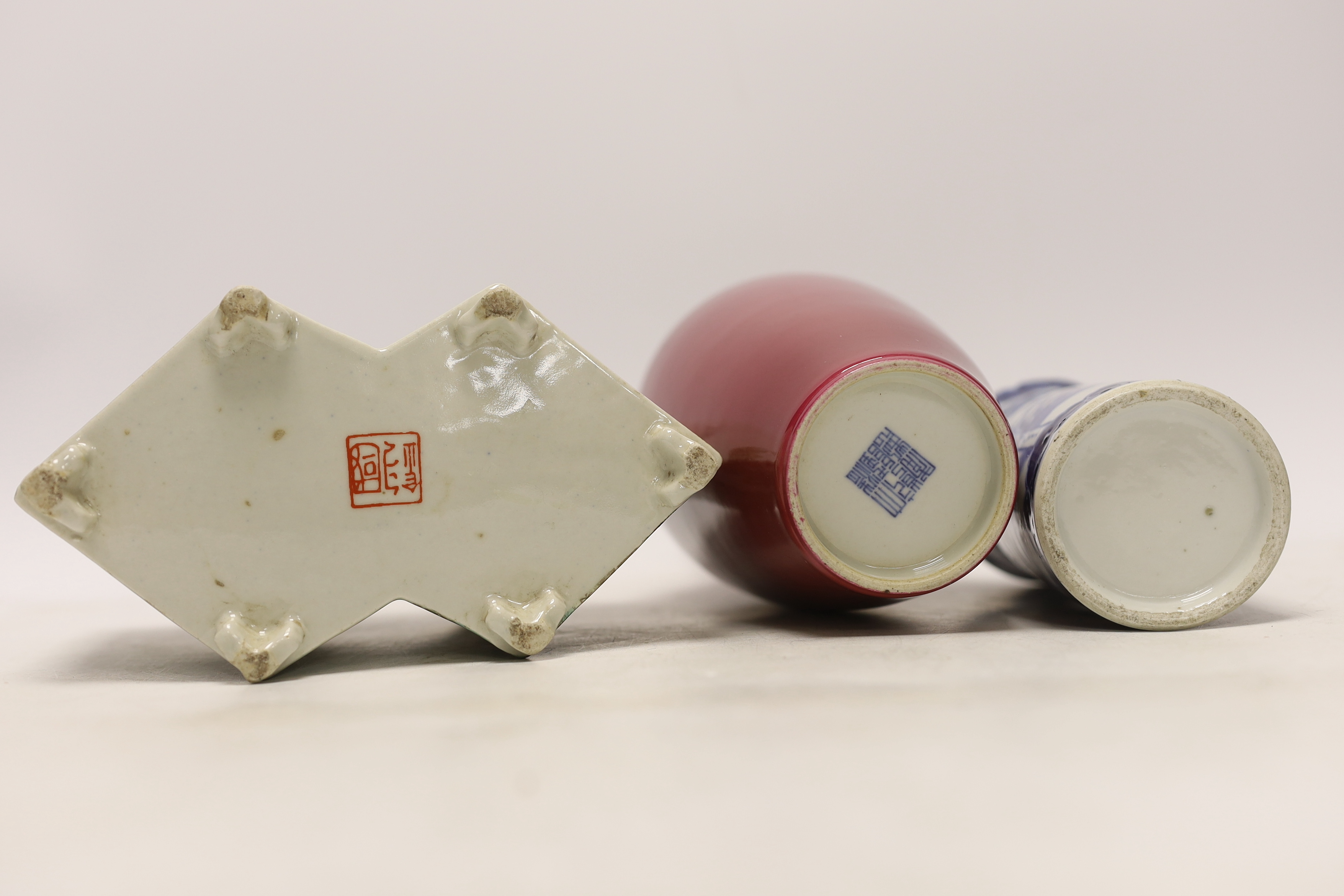 An early 20th century Chinese blue and white cylindrical vase, a ruby ground vase and an enamelled porcelain double lozenge vase, largest 24cm high (3)